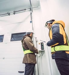 Two workers operating a commerical door