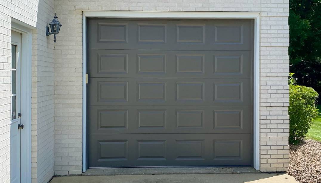 after - white brick garage with raised panel bronze garage door