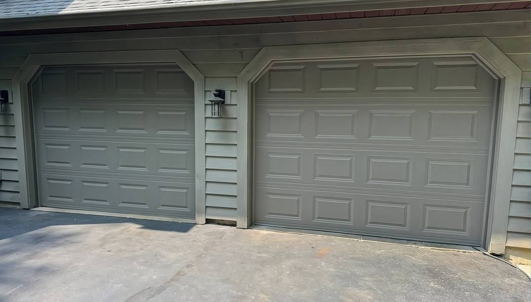 after - white paneled garage with two raised panel bronze garage doors