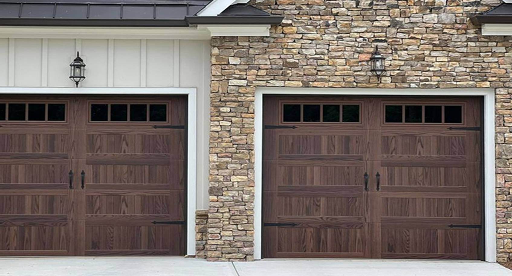 A closeup of two woodtone garage doors surrounded with panelling and brick