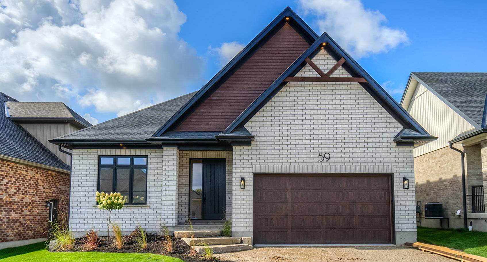 A white brick modern tudor house with a woodtone garage door