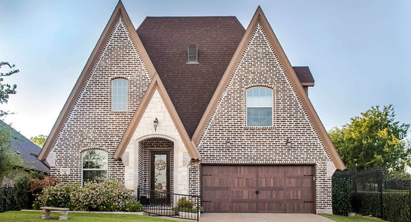 Pointed brick house in a modern tudor style with a woodtone garage door